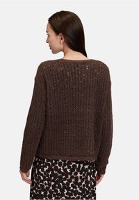 Bruine gehaakte trui met een losse pasvorm, gestructureerd patroon en brede mouwen, gecombineerd met een rok met luipaardprint.