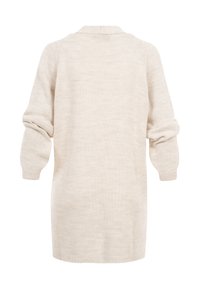 Pull long en tricot crème avec manches retroussées, poignets côtelés visibles et coupe ample et confortable, vu de dos.