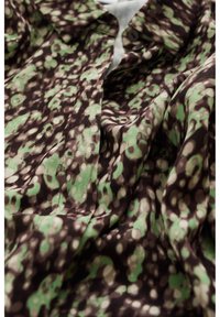 Brun och grön mönstrad tyg med blommönster, som har en slät struktur och mjuk fall; inkluderar knappar och en krage.