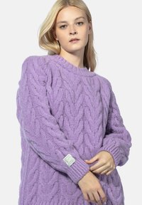 Liliowy sweter dzianinowy z wzorem w warkocze, ściągaczowymi mankietami i okrągłym dekoltem. Zawiera metkę na lewym rękawie. Miękka tekstura.