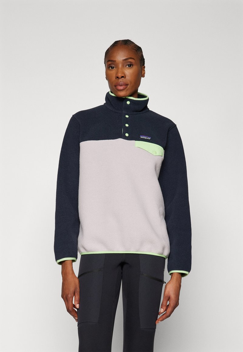Fleece-pullover i marineblå og lys grå med grønne detaljer, har høy krage, trykknapper og brystlomme. Myk tekstur.