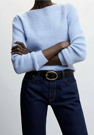 Un pull en maille côtelée bleu clair avec un large col et des manches longues, associé à un jean en denim bleu foncé et une ceinture noire avec une boucle ovale dorée.