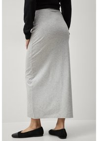 Grijze jersey maxi-rok met een aansluitende taille en een rechte silhoët, gecombineerd met zwarte ballerina's en een zwart t-shirt met lange mouwen.