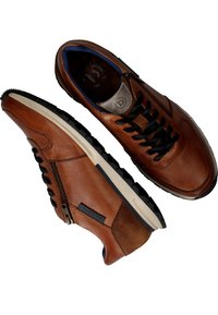 Bruine leren sneakers met zwarte veters, voorzien van een zijrits en een getextureerde hielaccent. Buitenzool is van zwart rubber met een witte tussenzool.