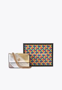 Borsa a tracolla metallica con sezioni diagonali argento e oro, superficie testurizzata, tracolla a catena, accanto a una scatola di imballaggio colorata.