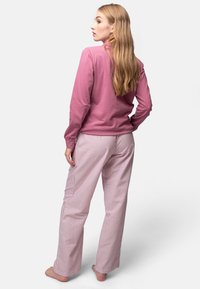 Maglietta rosa a maniche lunghe abbinata a pantaloni pigiama a righe rosa e bianchi. Il tessuto sembra morbido con una vestibilità comoda e un design a gamba dritta.