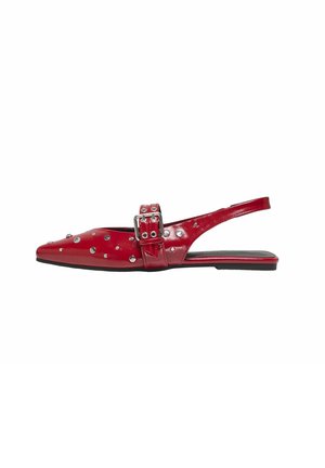 Scarpa slingback in pelle verniciata rossa con punta affusolata, decorata con borchie argentate e un grande dettaglio a fibbia. Suola piatta.