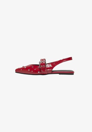 Zapato de charol rojo tipo slingback con puntera afilada, adornado con tachuelas plateadas y un gran detalle de hebilla. Suela plana.