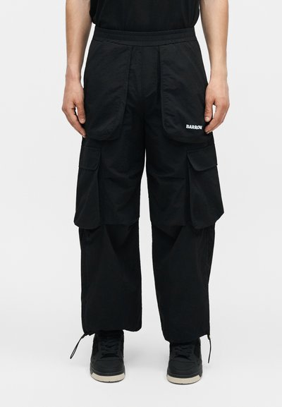 Μαύρο παντελόνι cargo με πολλές μεγάλες τσέπες, ελαστική μέση και το όνομα της μάρκας «BARROW» στην δεξιά μπροστινή τσέπη, φορεμένο με μαύρα αθλητικά παπούτσια.
