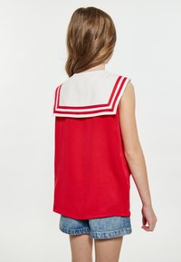 Rød ærmeløs bluse med hvid sømandkrave med røde striber. Stoffet ser glat og let ud, med en afslappet pasform og rundet kant.