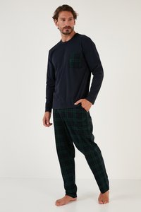 Cămașă bleumarin cu mânecă lungă, dotată cu un buzunar verde în carouri, asortată cu pantaloni în carouri verzi și negri. Material moale, croială lejeră. Model desculț.