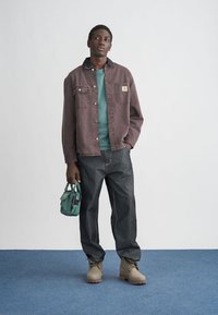 Καφέ τζιν μπουφάν, μπλε-πράσινο πουκάμισο, σκούρο μπλε τζιν, μπεζ μποτάκια, πράσινη τσάντα· διαθέτει τσέπες και αντίθετο γιακά στο μπουφάν.