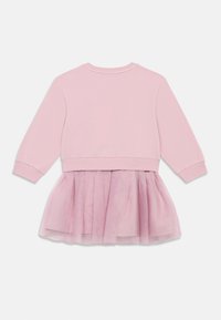 Ružičasti dukserica s dugim rukavima, s tilom preko suknje u svjetlijoj ružičastoj boji. Donji dio ima naboranu teksturu koja osigurava udoban fit.