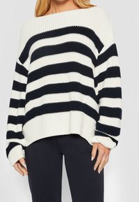 Maglione oversize lavorato a maglia a righe crema e blu navy, con scollatura a barca, maniche lunghe e polsini a coste. Texture morbida.