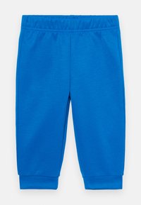 Μπλε φόρμες από μαλακό ύφασμα, με ελαστική μέση και στενές μανσέτες στους αστραγάλους. Ομαλή υφή, χωρίς ορατά σχέδια.