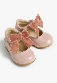 Chaussures en cuir verni rose avec un bout arrondi, dotées d'un nœud en velours rose sur la lanière et d'une semelle en caoutchouc pour une meilleure adhérence.