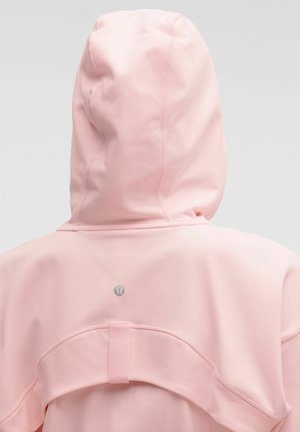 Zachtroze hoodie, bekeken vanaf de achterkant, met zichtbare naaddetails en een klein reflecterend Lululemon-logo onder de capuchon.