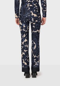 Blommönstrade byxor i marinblått och beige, designade med vida ben. Materialet är mjukt med en lätt lyster och har en solid svart mudd vid fållen.