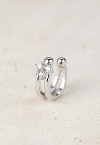 Silberring mit zwei gebogenen Bändern und einem zentralen, diamantähnlichen Stein sowie einem kleinen, sphärischen Akzent auf der gegenüberliegenden Seite. Glatte Oberfläche.