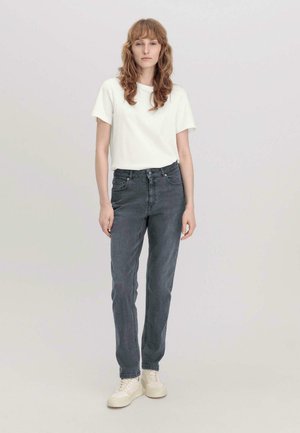 Weißes Baumwoll-T-Shirt kombiniert mit hoch geschnittenen, dunkelgrauen Jeans. Die Jeans haben einen klassischen Schnitt und werden mit neutralen Sneakers styled.