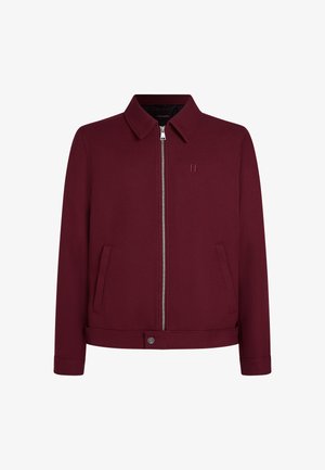 Chaqueta burdeos hecha de tejido texturizado, con cierre de cremallera, dos bolsillos laterales y cuello con solapa. Detalle de marca minimalista.