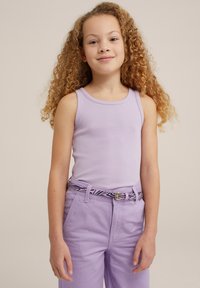Svijetlopurple majica na bretele sa rebrastim uzorkom u kombinaciji s odgovarajućim ljubičastim hlačama. Remenje se ističe crno-bijelim uzorkom zebre, s detaljem zlatne kopče.