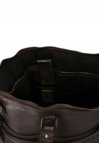 Interno di una borsa in pelle marrone con apertura zip, foderata in tessuto scuro e dotata di molteplici tasche per un'organizzazione efficace. Accenti in metallo notevoli.