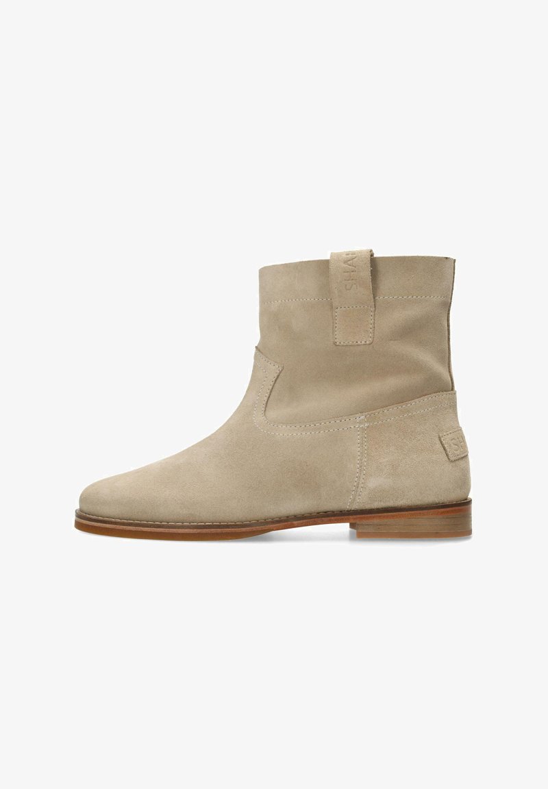 Bottine en suédine beige avec un bout arrondi et une tige courte. Dotée d'une languette et de coutures discrètes. La semelle en bois ajoute un contraste.