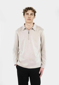 Ljust beige sweatshirt med zip-krage, långa ärmar och mjukt tyg. Har en ren design och rak skärning.