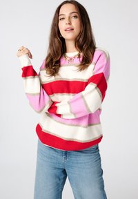Gestreepte gebreide trui in rood, roze en crème, met horizontale banden en een geribbelde textuur. Ronde halslijn en ontspannen pasvorm.