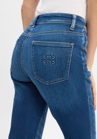 Schmal geschnittene blaue Jeans mit einer subtilen Textur. Verfügt über eine einzigartige Logo-Stickerei auf der Gesäßtasche und traditionelle Nahtdetails.