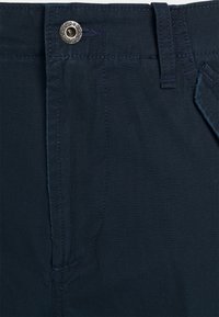 Tmavě modré bavlněné kalhoty s hladkou texturou, vybavené stříbrným kovovým knoflíkem, tónovaným prošitím a bočními kapsami.