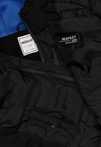 Black puffer jacket interior with blue mesh lining, featuring tags for "minoti" and "RESPECT." Includes zippered pockets and textured fabric.