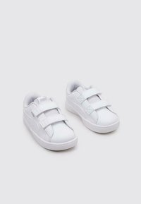 Białe buty sportowe wykonane z gładkiego materiału syntetycznego, z podwójnymi zapięciami na rzep, zaokrąglonym noskiem i wyściełanymi podeszwami.
