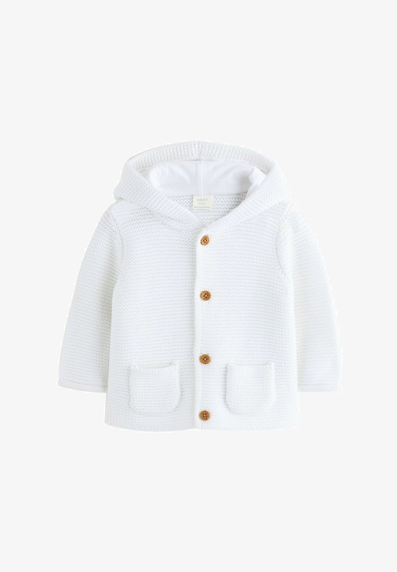 Gilet de bébé en tricot blanc avec capuche, trois boutons en bois et poches avant. La texture est chaleureuse, avec un motif côtelé.