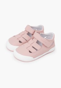 Zapatos de cuero rosas con punta cerrada, múltiples cortes y tiras de Velcro. Suela de goma blanca con agarre texturizado y forro interior suave.