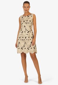 Mouwloze jurk met bloemenkant overlay in ivoor en zwart. Geschulpte zoom, aansluitende silhouet en ingewikkelde borduurdetails.