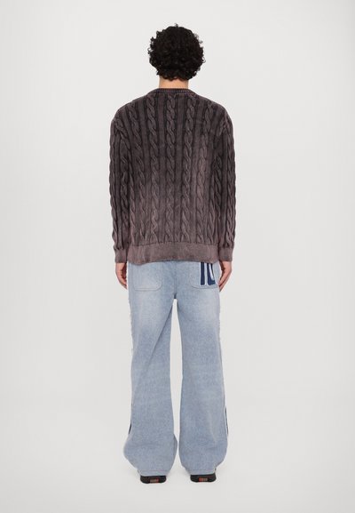 Pull en tricot torsadé de couleur taupe foncé avec un ourlet côtelé. Associe avec un jean ample bleu clair doté de bandes latérales et de deux poches arrière.