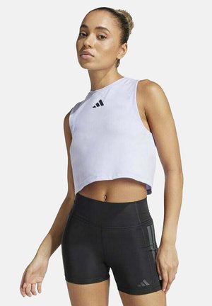 Light lavender cropped athletic tank top with black Adidas logo, paired with high-waisted black shorts featuring side stripes and smooth texture.