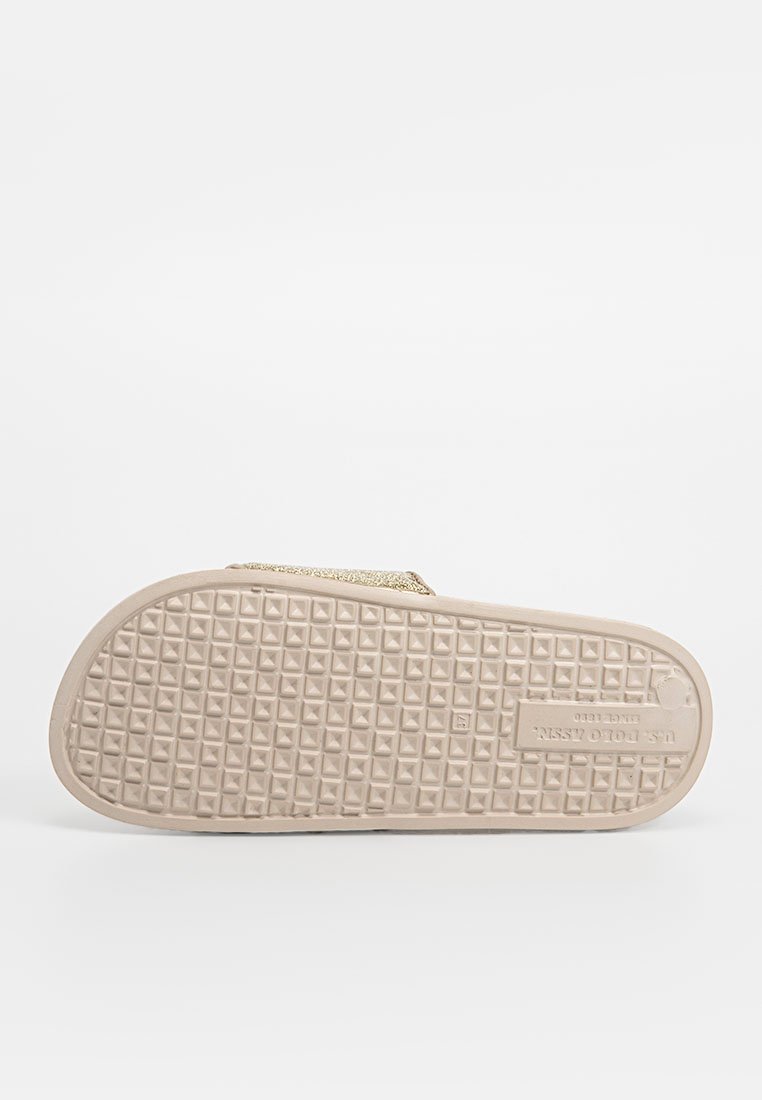 Beige Slipper mit einer strukturierten Gummisohle, ausgestattet mit einem goldenen Glitzerband über dem Obermaterial und einem gemusterten Profil für besseren Halt.