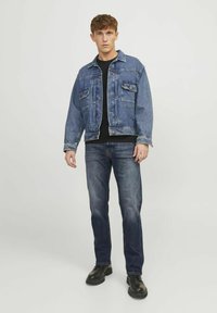 Denim jakna u srednje Plavoj boji, sa dva džepa na grudima i dugmadi na prednjoj strani. Nosena preko crne majice, u kombinaciji sa tamnoplave traperice i crnim čizmama.