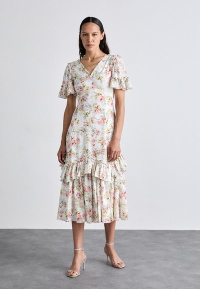 Robe midi imprimée florale en blanc avec des accents roses et verts. Dotée d'un décolleté en V, de manches ballons et d'un ourlet à volants en étages.