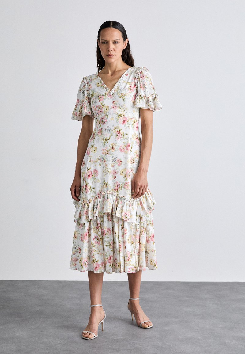 Abito midi a stampa floreale bianco con accenti rosa e verde. Presenta una scollatura a V, maniche a sbuffo e orlo a strati con volant.