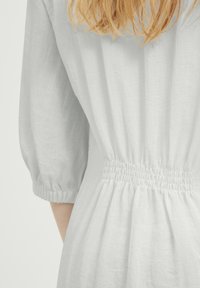 Rochie din in de culoare gri deschis, cu elastic pe talie și mâneci trei sferturi, având o textură moale.
