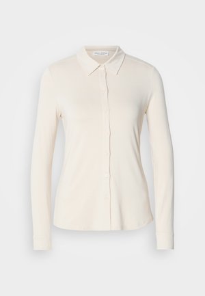 Lange mouw blouse in licht crčme, gemaakt van soepel stof. Heeft een klassieke kraag en knopen aan de voorkant. Eenvoudig, aansluitend ontwerp.