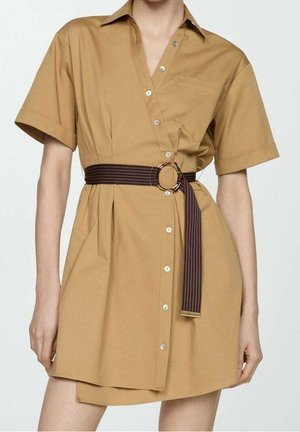 Robe chemise à manches courtes couleur beige avec boutons devant et ceinture rayée foncée à boucle circulaire cintrant la taille.