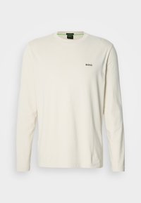 Tricou crem cu mânecă lungă din bumbac, având guler rotund și un mic logo negru "BOSS" pe piept. Material neted și ușor.