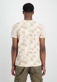Kortärmad beige t-shirt med abstrakt ljusbrun och krämfärgad mönster, gjord av mjukt tyg, med rundad halsringning och normal passform.