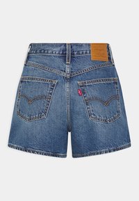 Short en denim bleu Levi's avec deux poches arrière, coutures orange, passants de ceinture et un patch en cuir marron de la marque sur la ceinture droite.