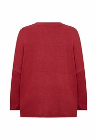 Crvena majica dugih rukava s opuštenim krojem, koja ima okrugli izrez i mekani, teksturirani materijal. Jednostavan dizajn, bez vidljivih uzoraka ili ukrasa.